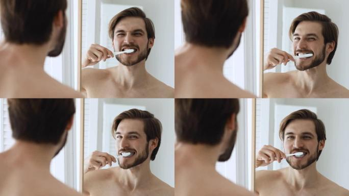 年轻快乐的裸男用牙刷和牙膏刷牙。