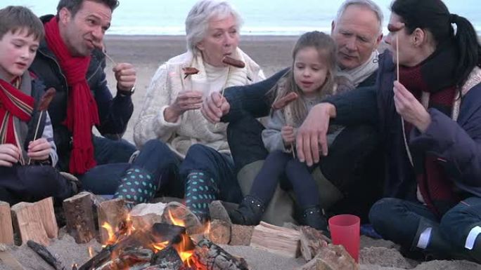 在冬季海滩上烧烤的多代家庭