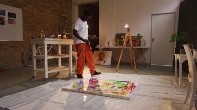 非裔美国男艺术家在艺术工作室的画布上倒颜料