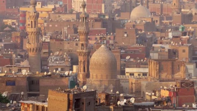 缩小开罗伊斯兰区的房屋和清真寺的镜头。鸟类在埃及开罗的清真寺和宣礼塔的背景下飞翔