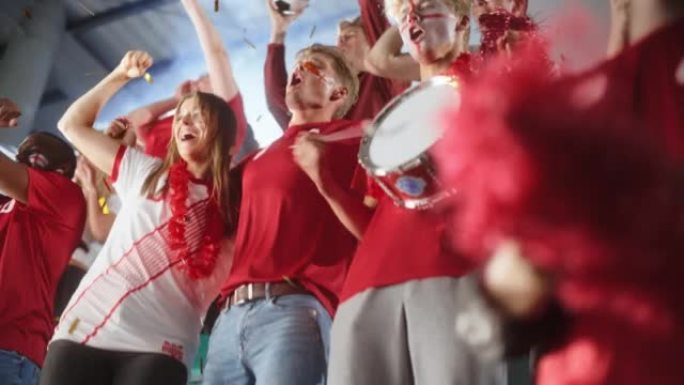体育馆活动: 一群球迷为红色足球队获胜而欢呼。人们庆祝进球，冠军胜利。一群画脸的朋友玩得开心。低角度