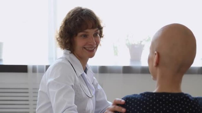 与癌症患者交谈的肿瘤学家触摸她的肩膀表示支持