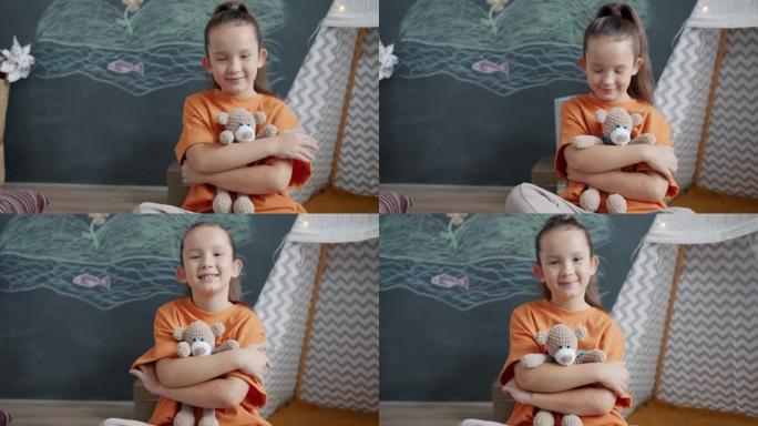 可爱的小女孩拥抱泰迪熊并在公寓里微笑的慢动作肖像