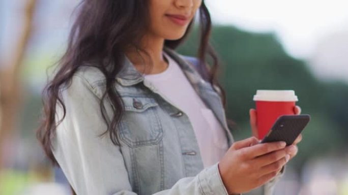 亚洲妇女使用智能手机并拿着外卖咖啡