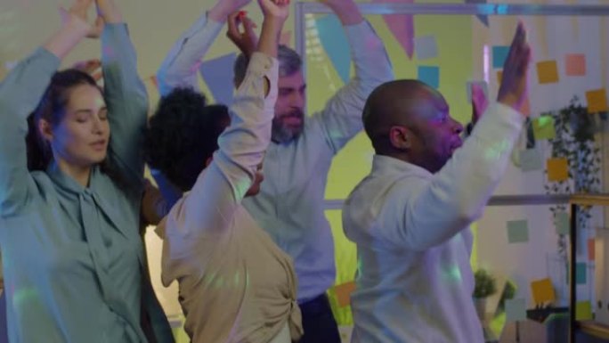 晚上，多元化的员工在工作场所跳舞，享受庆祝活动