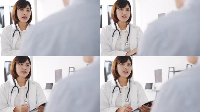 年轻的亚洲女性医生使用剪贴板正在发表重大新闻谈话，讨论结果或症状与男性患者坐在健康诊所的桌子上。