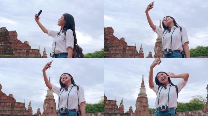 年轻的亚洲背包客博主女人休闲自拍视频通话手机分享在线直播观众在宝塔古城一起旅行。