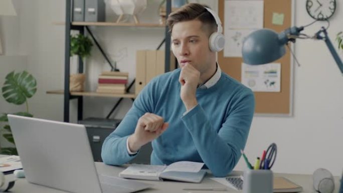 无忧无虑的商人与笔记本电脑一起工作，戴着耳机听音乐，在办公室跳舞