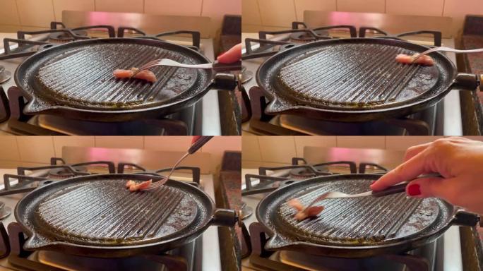 女人用一块脂肪给铸铁锅上油或上油，以防止肉粘在铸铁上。特写。4k分辨率。