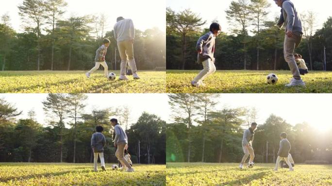 亚洲小男孩在公园与父亲在户外踢足球