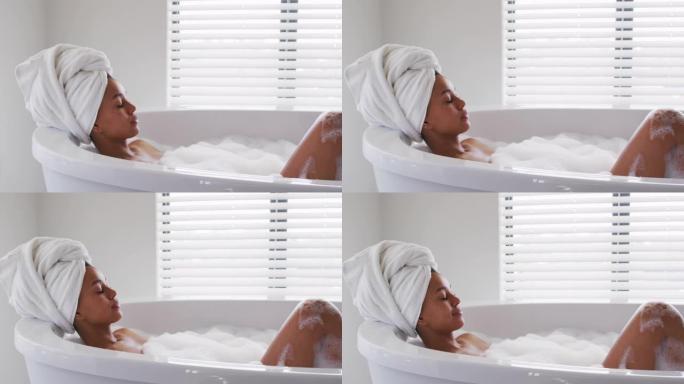非裔美国妇女在家里浴室的浴缸里放松