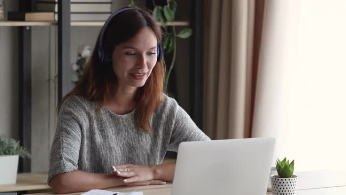 女人戴着耳机看着笔记本电脑屏幕使用videoall进行谈判