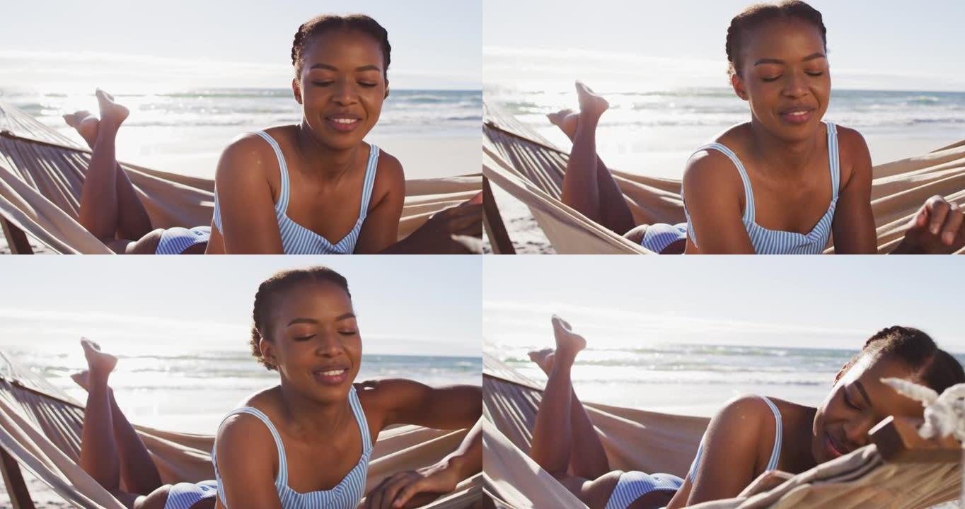 非裔美国妇女躺在海滩的吊床上使用数字平板电脑