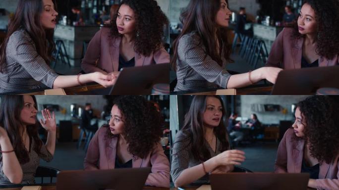 面试概念。两名年轻漂亮的多民族妇女使用笔记本电脑交谈，在咖啡馆商务午餐会上一起工作。