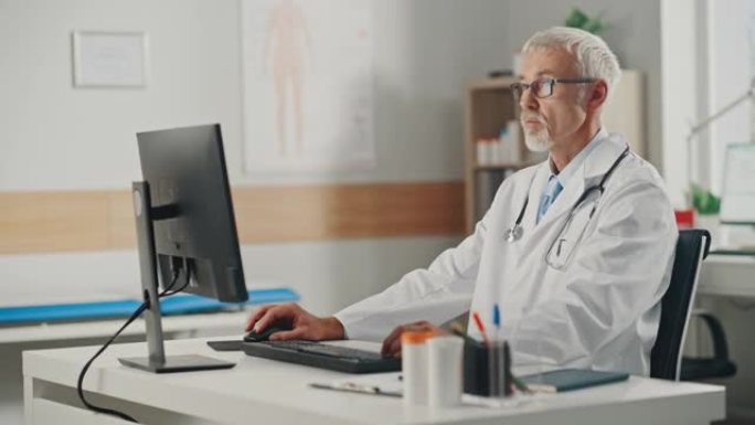 经验丰富的中年男医生穿着白大褂在办公室的个人电脑上工作。高级医疗保健专业人员，负责测试结果，患者治疗