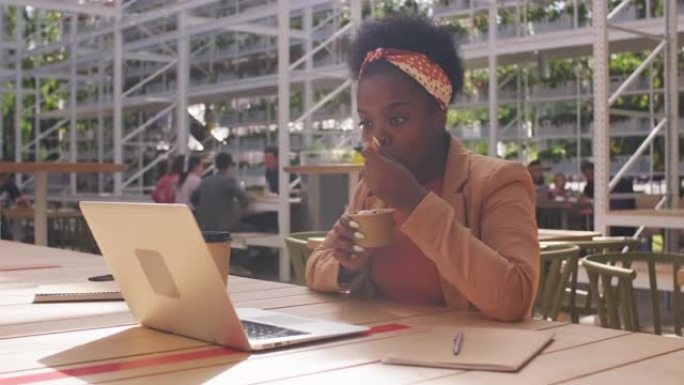黑人女商人享受冰淇淋并在笔记本电脑上工作