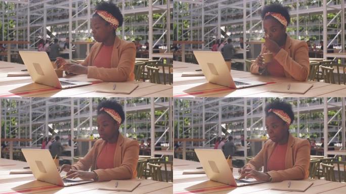 黑人女商人享受冰淇淋并在笔记本电脑上工作