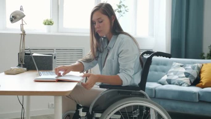有动力的残疾人自由职业者在家里坐在轮椅上打字和做笔记