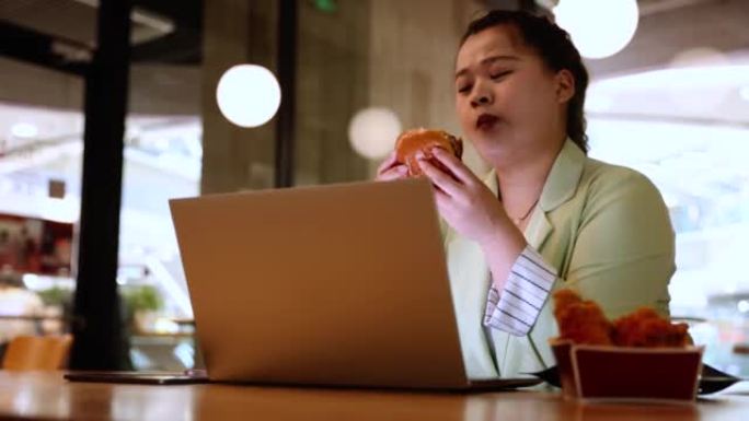 女商人在使用笔记本电脑时吃快餐