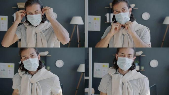 帅气混血男子在办公室戴上医用口罩的慢动作肖像