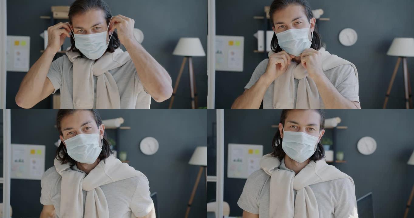 帅气混血男子在办公室戴上医用口罩的慢动作肖像