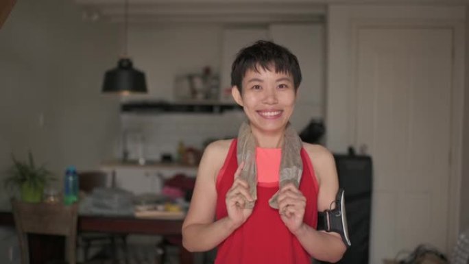穿着运动服的亚洲中国美女带着露齿微笑看着相机快乐站在客厅