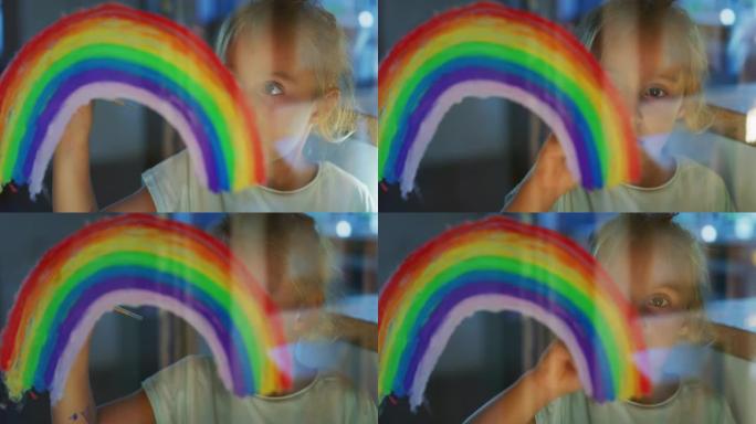 一个可爱的小创意快乐微笑的学龄前女孩画家的真实镜头正在家里厨房的窗户玻璃上画彩虹。