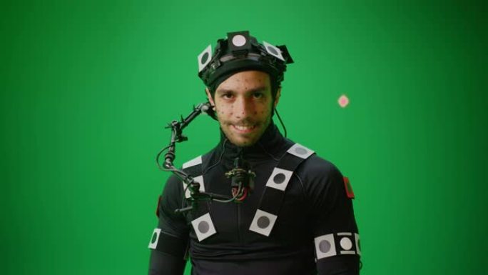 穿着运动字幕服和头部装备与绿屏背景合影的演员肖像。电影制片厂用色键拍摄大片。中等镜头看着相机