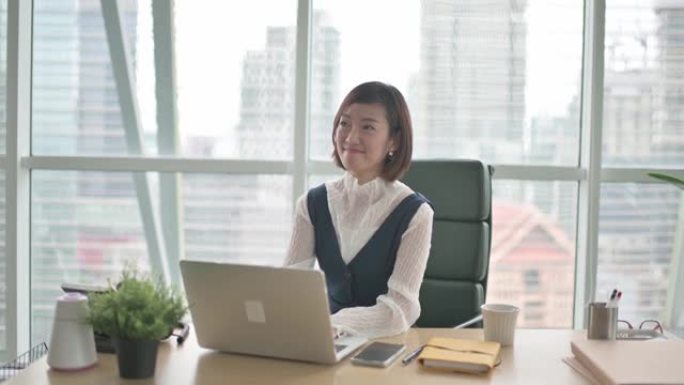 亚洲华裔美女首席执行官高级管理层看着相机在办公室的办公桌前微笑