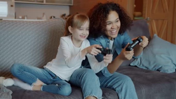 可爱的小女孩在家和美国黑人保姆玩电子游戏的慢动作