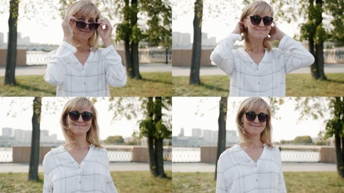 美丽的成年女性戴着时尚的太阳眼镜站在城市户外微笑的肖像