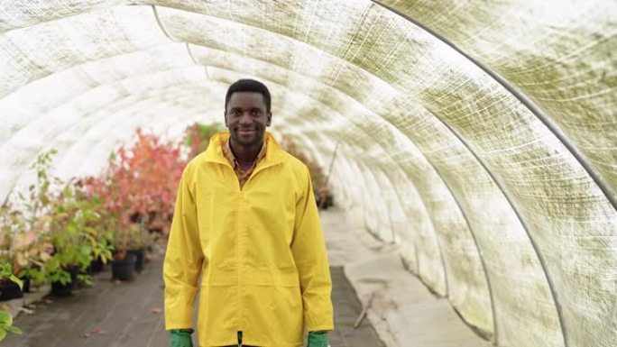 非洲男子园丁的肖像在温室里用水罐