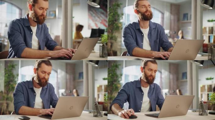一位英俊的长发大胡子经理坐在创意办公室的办公桌前的肖像。时尚的男人在营销公司使用笔记本电脑。在后台工