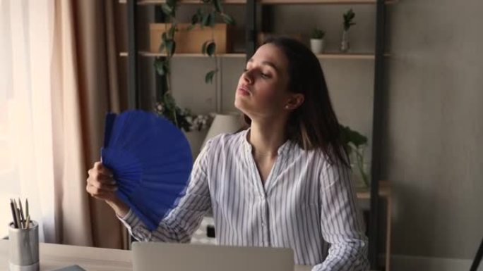 坐在工作场所的女人波浪风扇减少室内的热空气