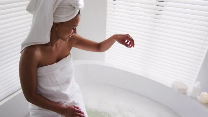 非裔美国妇女在家中浴室的浴缸里碰水