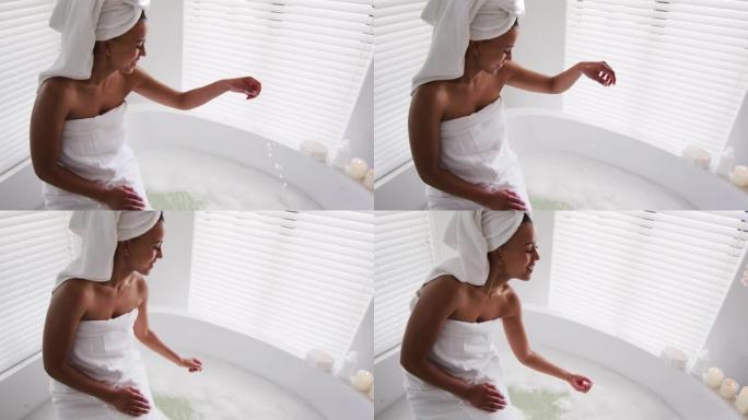非裔美国妇女在家中浴室的浴缸里碰水