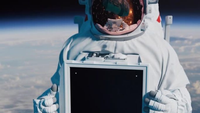 宇航员一只手拿着一块方形的平板电脑，另一只手表现出竖起大拇指的手势。宇航员的形象，一切都很好，很出色