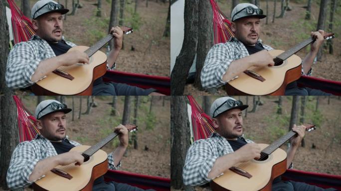 帅哥游客弹吉他，在野生森林的吊床上唱歌摇摆，享受旅行
