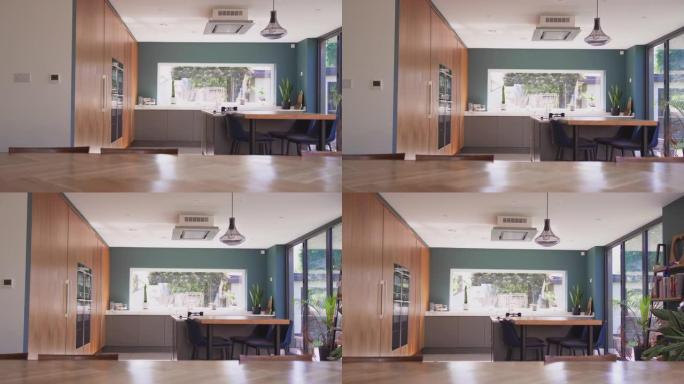 相机跟踪美丽的当代厨房的内部，配有合适的电器和储物空间，可以看到慢动作拍摄的花园景色