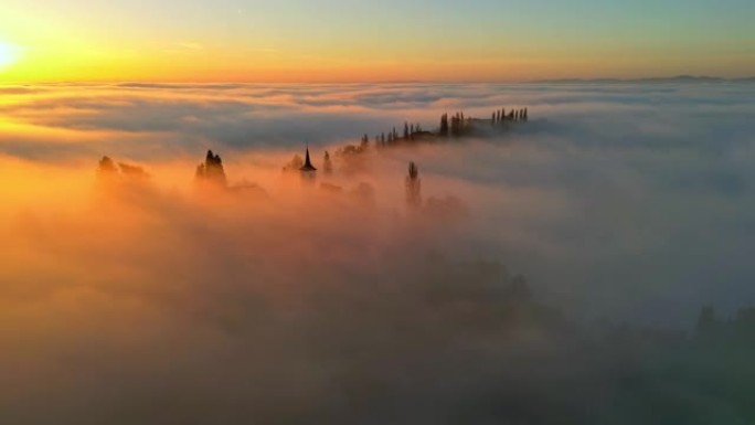 日落时，空中浓雾笼罩在山顶的教堂上