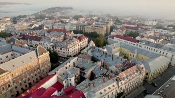 飞越乌克兰切尔诺夫策的城市中部和老房子。早晨的灯光下乌克兰切尔诺夫策市的空中无人机视图，背景上的小雾