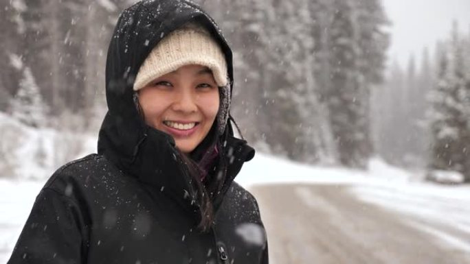 亚洲妇女在下雪时看着相机的肖像