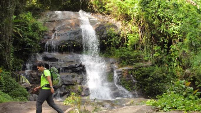 雄性徒步旅行者在雨林中徒步旅行在绿色森林中的小溪瀑布探险