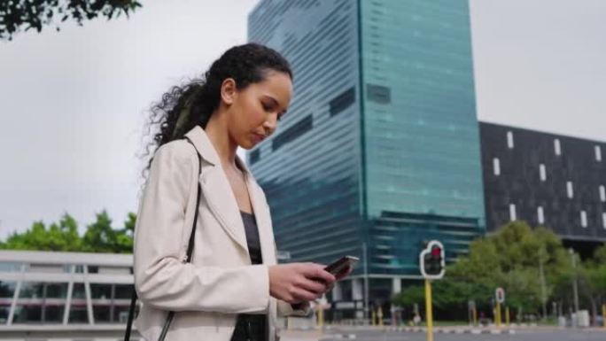 一名年轻的女商人从下面在城市里等出租车时用手机发短信。雄心勃勃的企业家在早上上班时浏览应用程序和社交