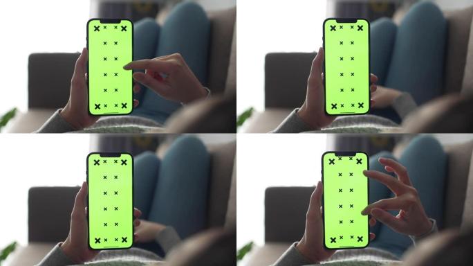 女人在沙发上使用绿屏智能手机时躺下