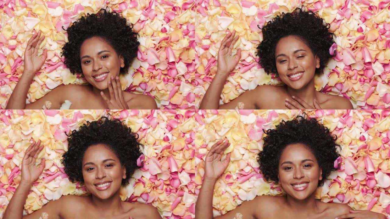 女性美女肖像躺在花坛上。性感的黑人多民族女性，有着非洲的头发，自然、干净、健康的皮肤摆姿势，微笑着。