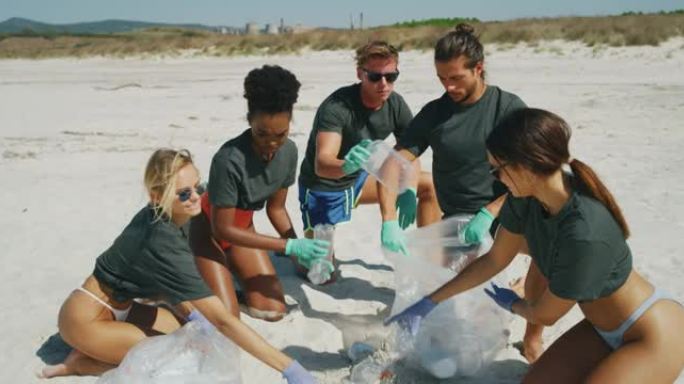 在阳光明媚的日子里，年轻志愿者团队的慢动作在海边捡拾塑料垃圾，以保护环境。