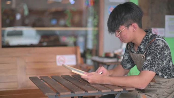 亚洲中国年轻咖啡馆咖啡师服务员自助餐厅工作人员在咖啡馆餐厅外面准备营业的黑板上用粉笔写 “开放” 字