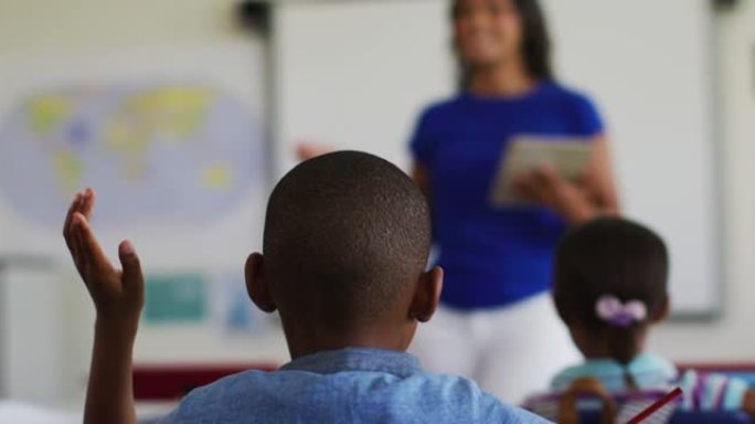坐在教室里的非洲裔美国男孩在课堂上举手回答问题
