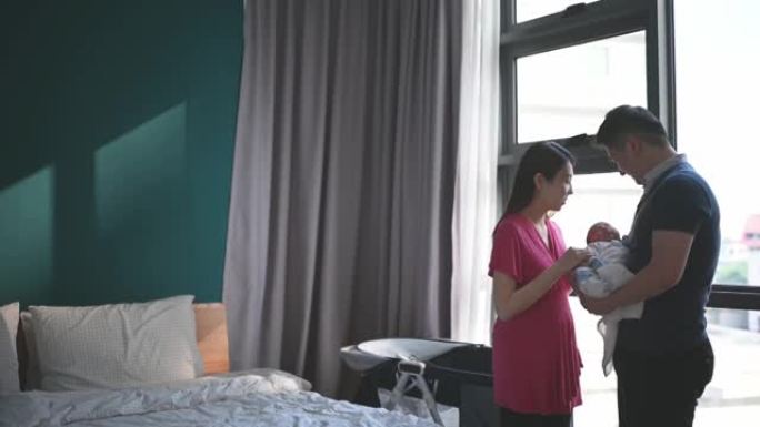 亚洲华裔父母带着爱在卧室里抱着他们刚出生的男婴